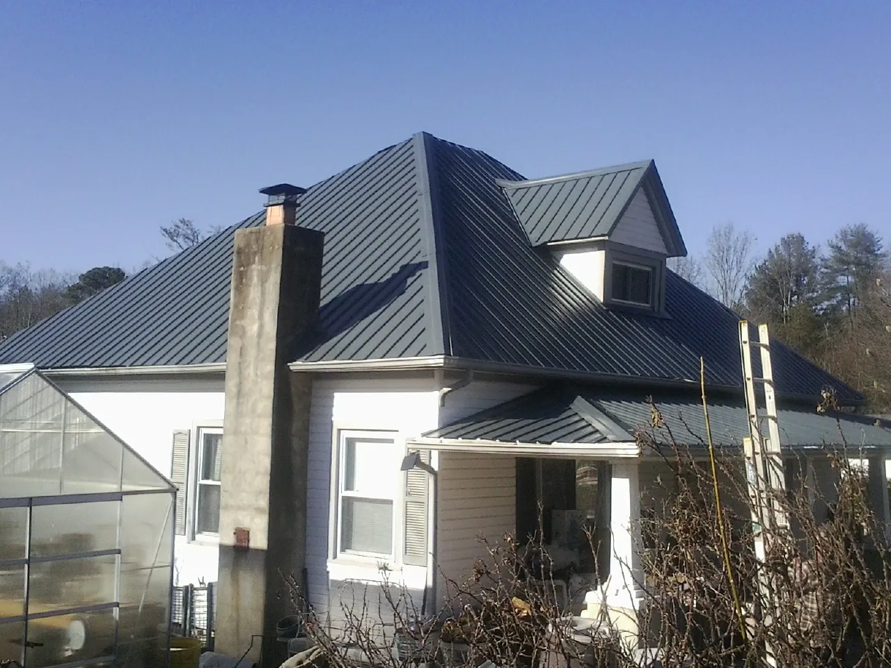 Dark blue standing seam metal roof on a white farmhouse with dormer — Slate & Tile Roof Repair by Roofing Brothers in San Pablo