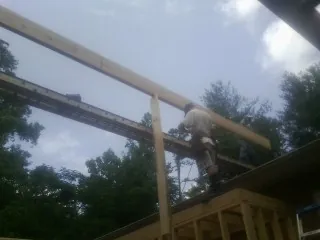 Carpenter setting a ridge beam over a new addition frame in San Pablo