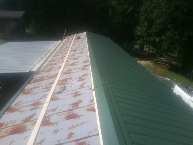 Old rusted panels beside newly installed green metal roofing — Wind Damage Roof Repair by Roofing Brothers in San Pablo