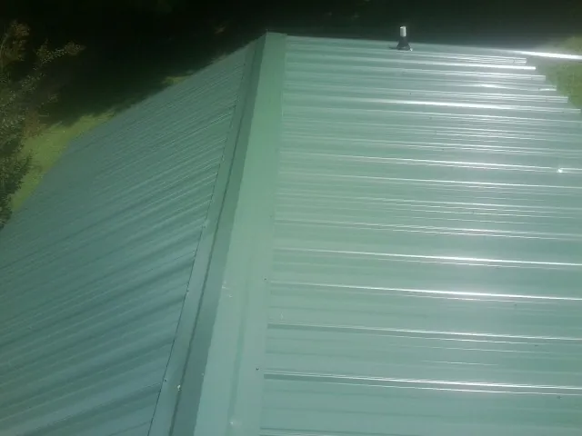 New green metal panels meeting at the ridge of a roof — Flat Roof Repair work by our crew in San Pablo