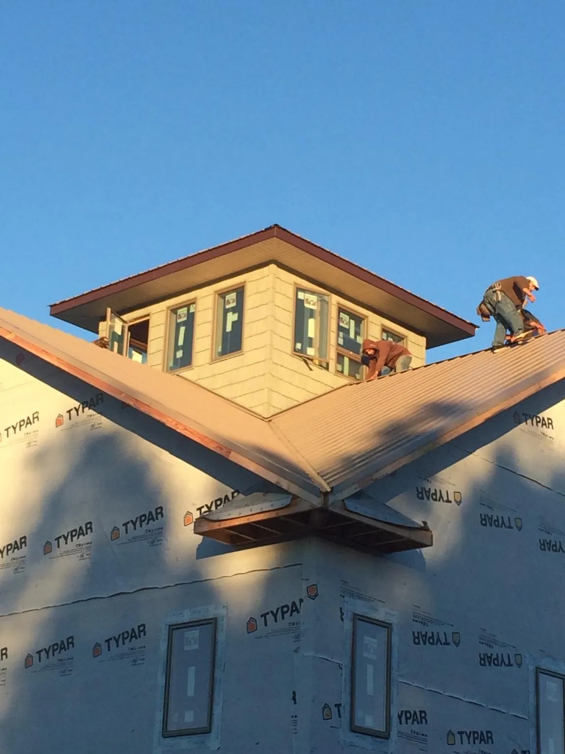 Roofers working around a rooftop cupola on a new metal roof at sunset — Roof Waterproofing in San Pablo by Roofing Brothers